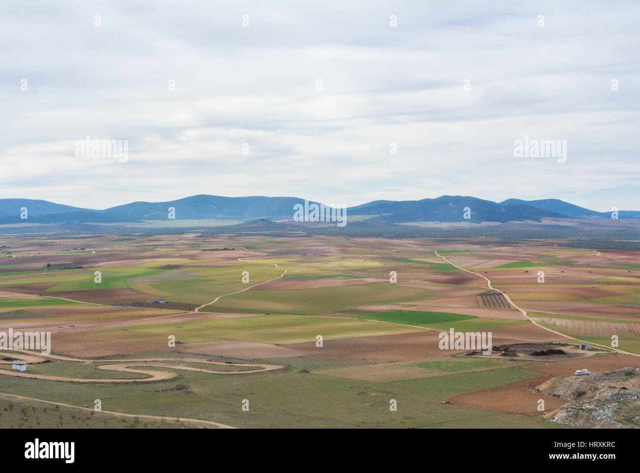 Vue d'une colline de champs, de fermes et de montagnes près de Consuegra ville au printemps jour nuageux. Banque D'Images