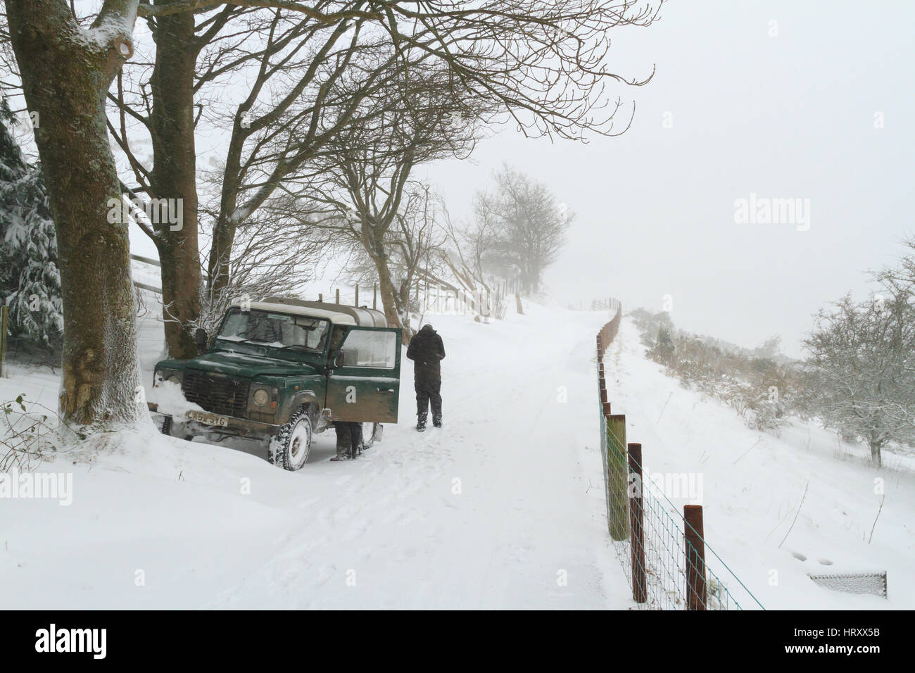 Fermier et sa Landrover tente d'atteindre au cours de l'élevage conditions de blizzard dans le Nord du Pays de Galles Llangollen Banque D'Images