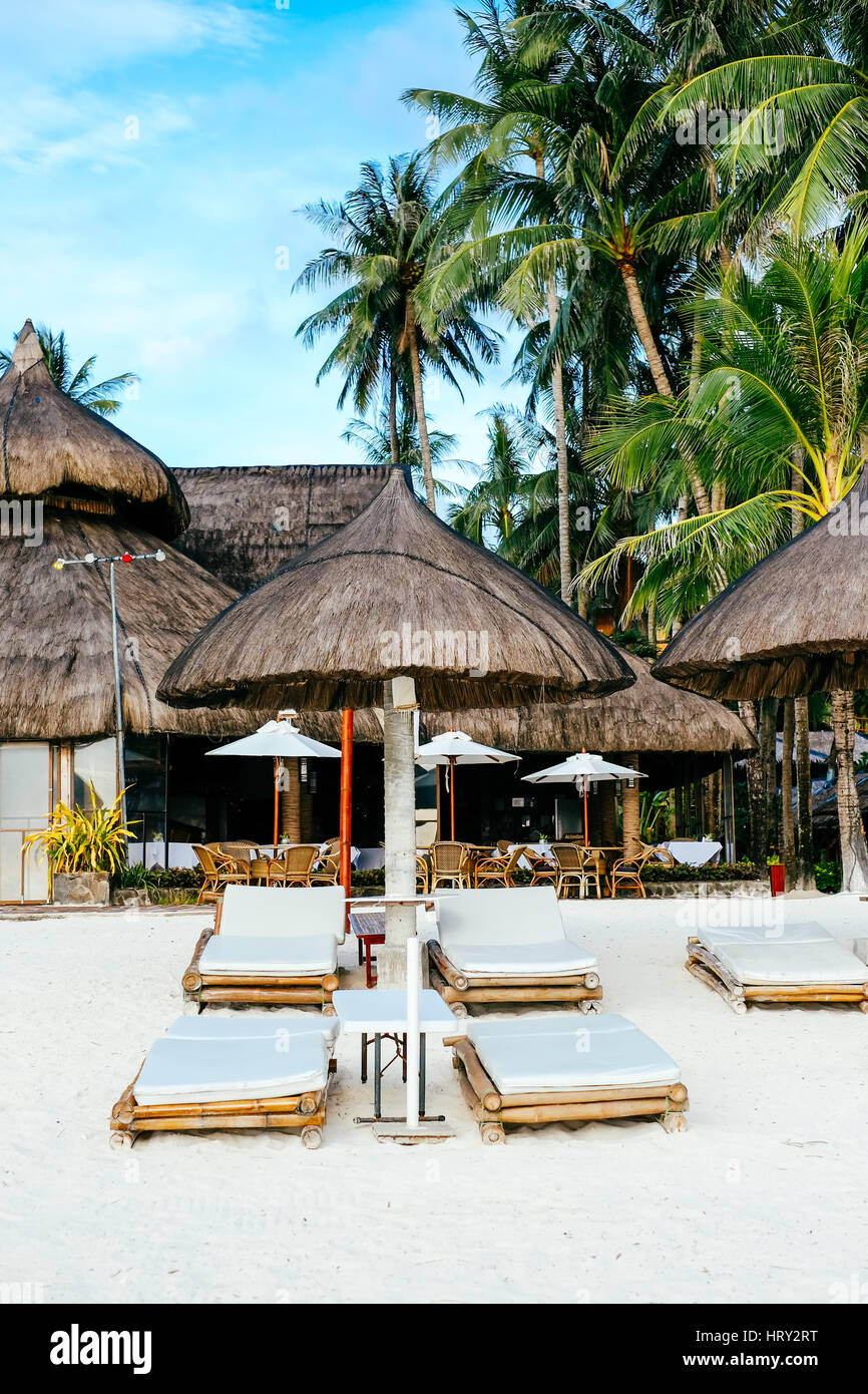 Nipa hut pare-soleil avec transats en bambou sur la plage de sable de corail blanc Banque D'Images