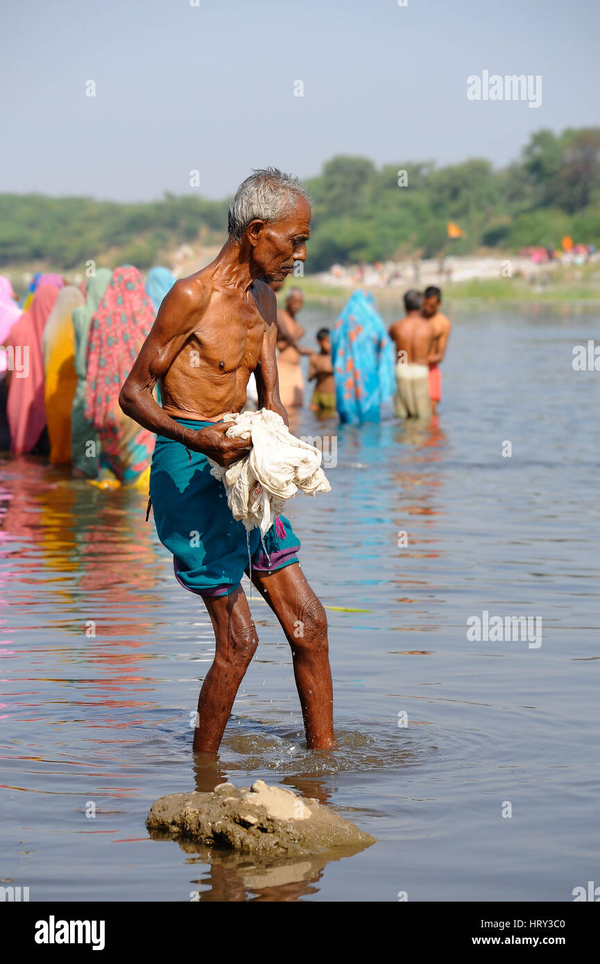 Un homme wahses son dhoti chiffon avant d'un groupe de personnes bain rituel à Baneshwar Mela Banque D'Images