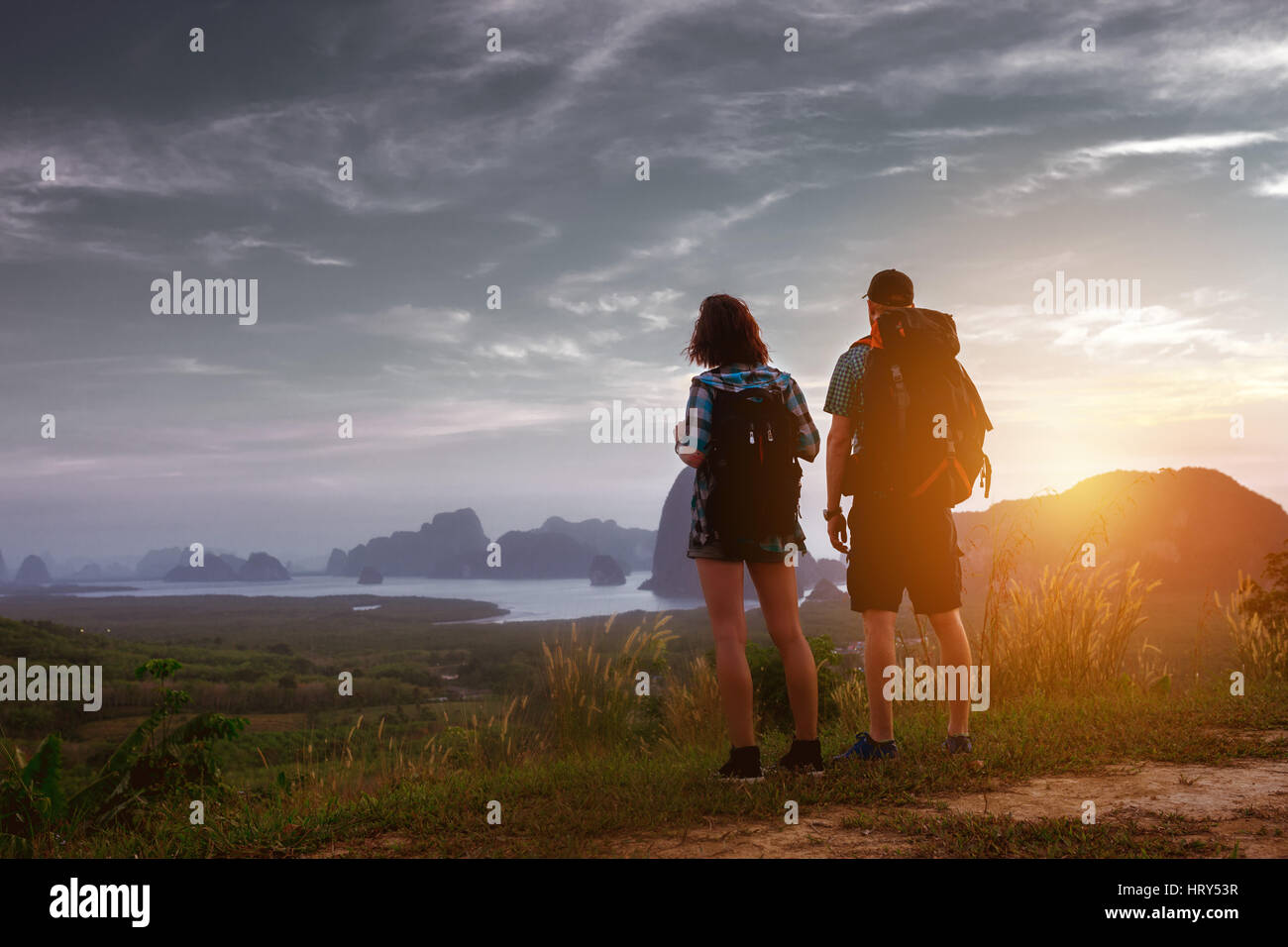 Couple de backpackers se trouve au lever ou au coucher du soleil en mer et d'îles en toile de fond. Concept du tourisme Banque D'Images