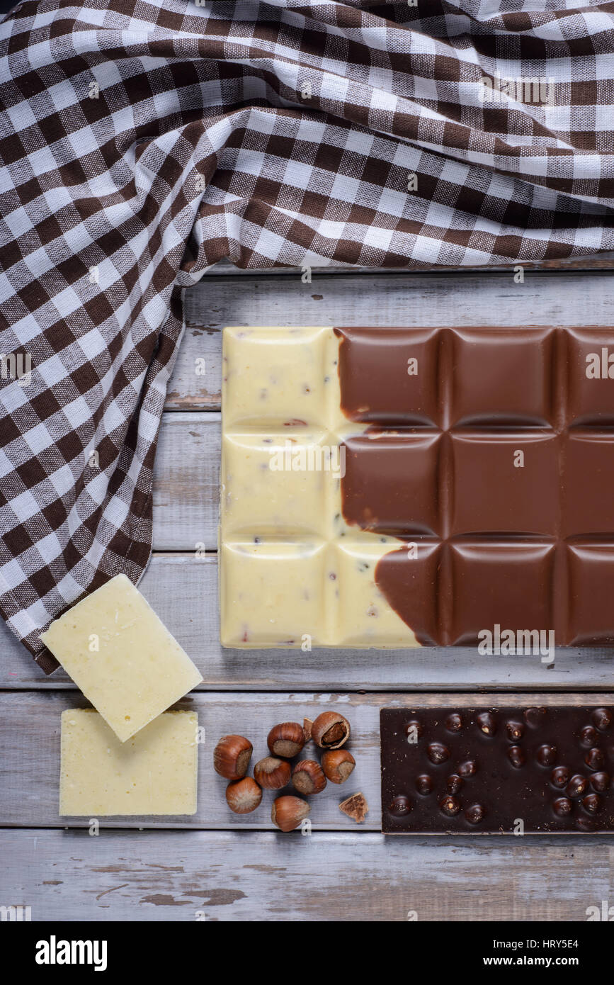 Morceaux de chocolat, tuile de noix et graines de cacao sur fond de bois Banque D'Images