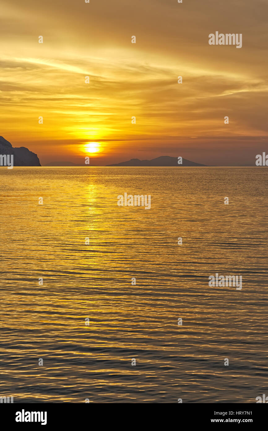 Coucher du soleil sur la plage avec de belles jaune et orange ciel dramatique. Silhouette d'une île très en avance en vue. Banque D'Images