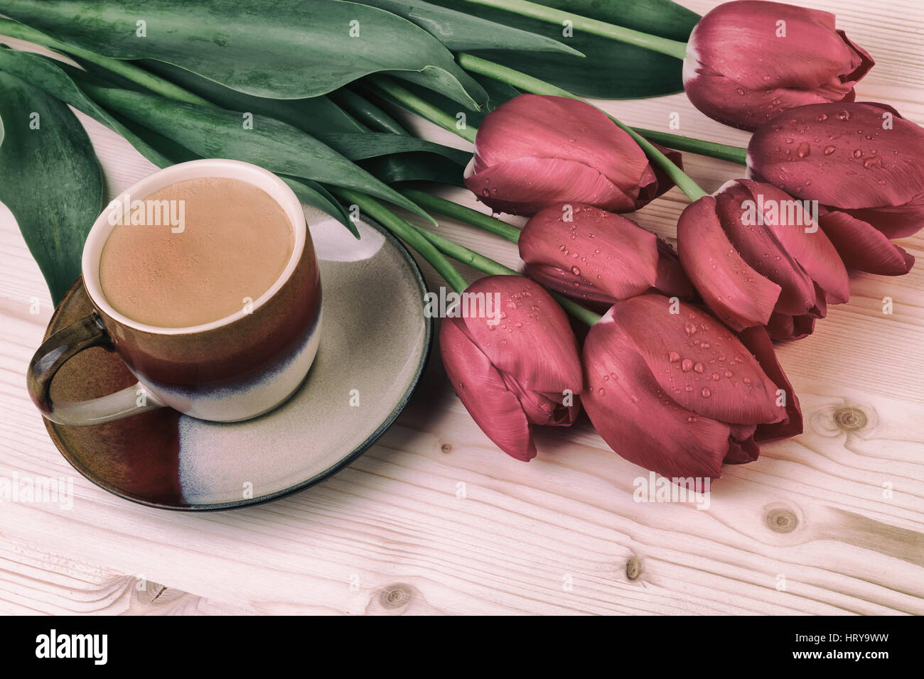 Tasse de café avec des tulipes rouges sur la table en bois. Café au style vintage Banque D'Images