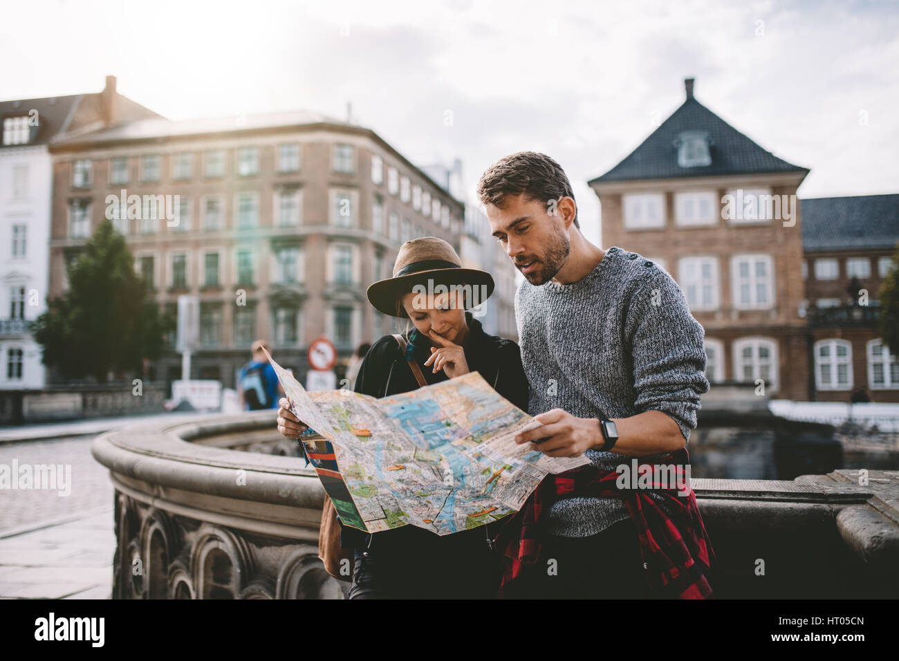 Jeune couple à la recherche lors d'une carte de navigation de la ville. Les touristes à trouver leur chemin à la carte à un comité permanent sur la rue. Banque D'Images