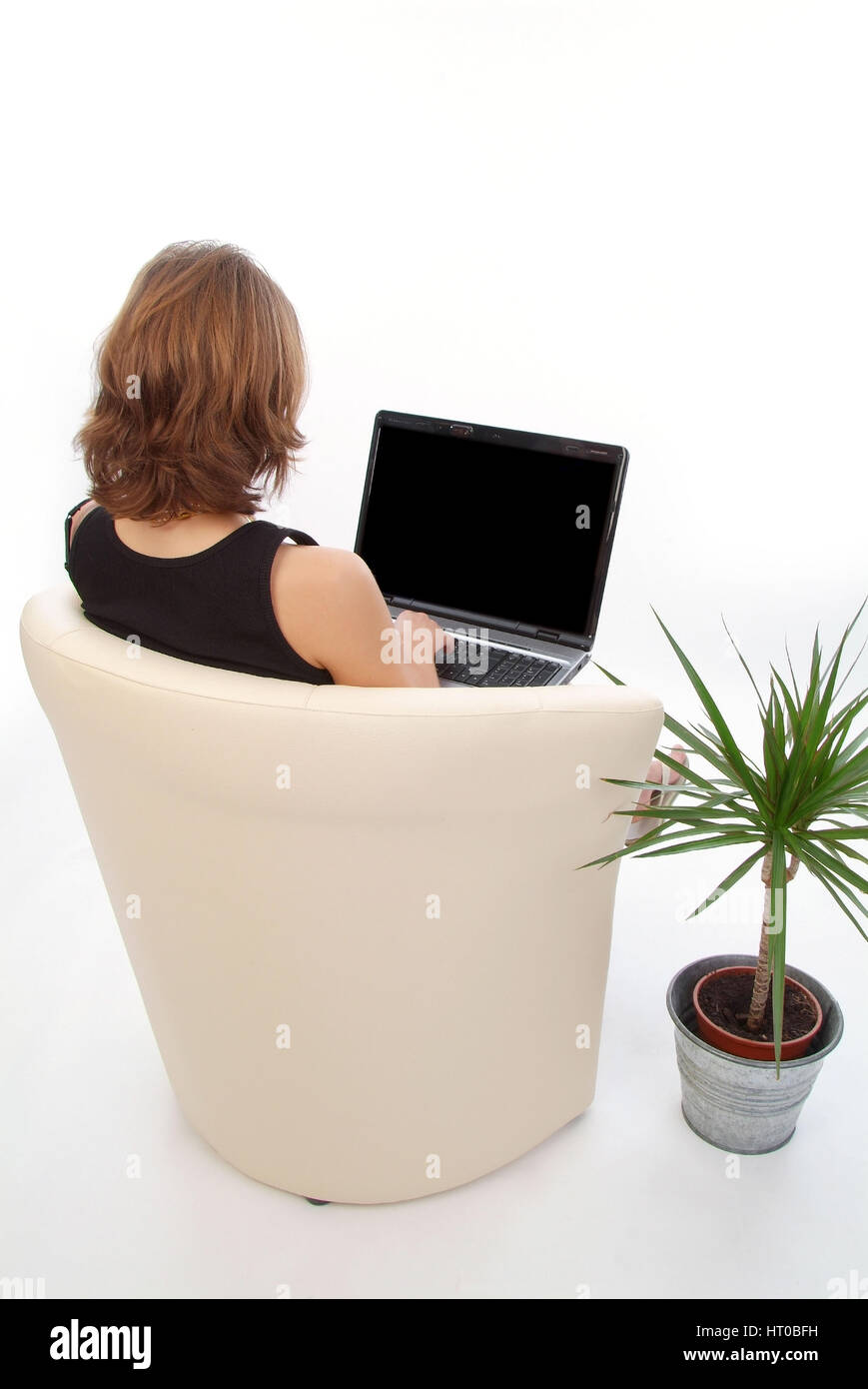 Junge Frau sitzt und arbeitet im Lederstuhl suis coffre - woman using laptop Banque D'Images