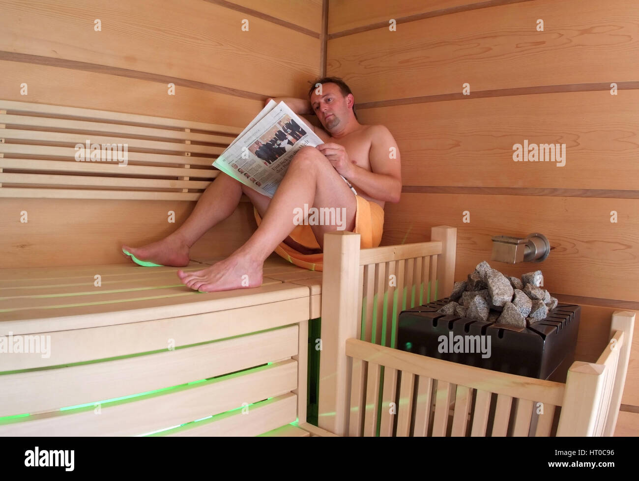 Mann liest Zeitung en Sauna - femme dans un sauna Banque D'Images