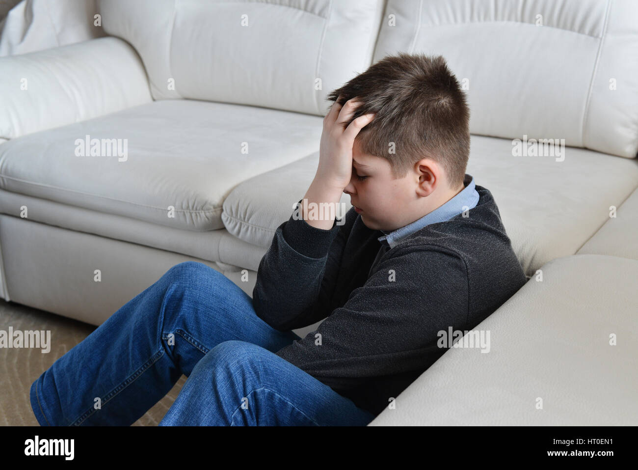 Adolescent perturbé 13 ans assis près de la table et l'holding his head in hands Banque D'Images