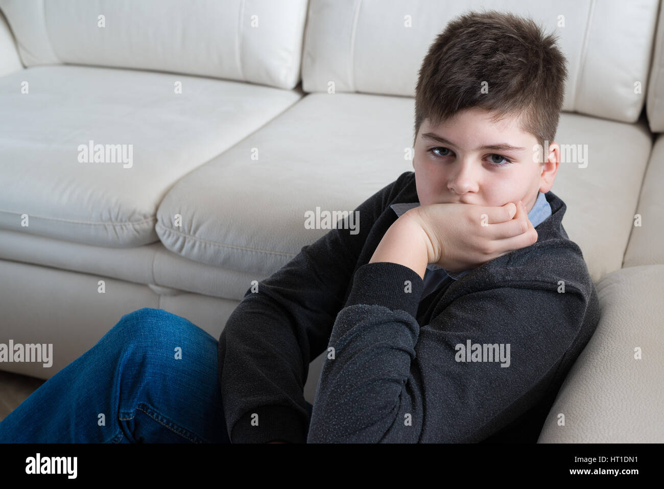 13 ans garçon assis près du canapé dans la chambre Banque D'Images