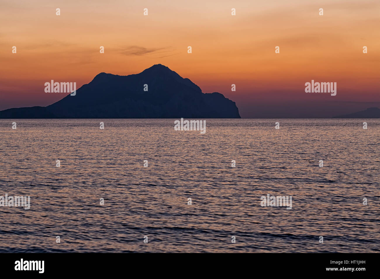 Coucher du soleil sur la plage avec de belles jaune et orange ciel dramatique. Silhouette d'une île très en avance en vue. Banque D'Images