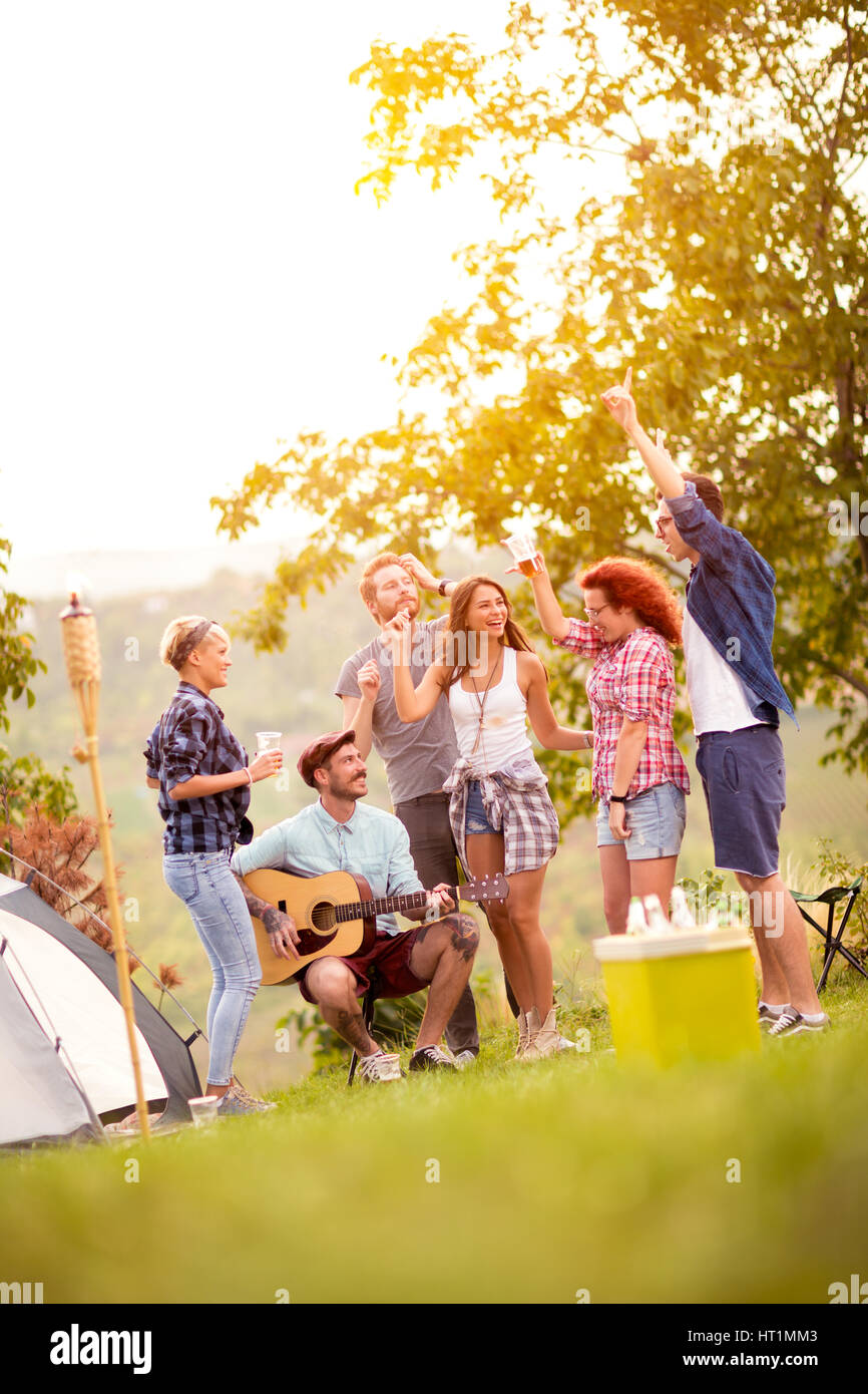 Groupe de jeunes amis de la danse et avoir du plaisir avec la musique au camp dans le bois vert Banque D'Images