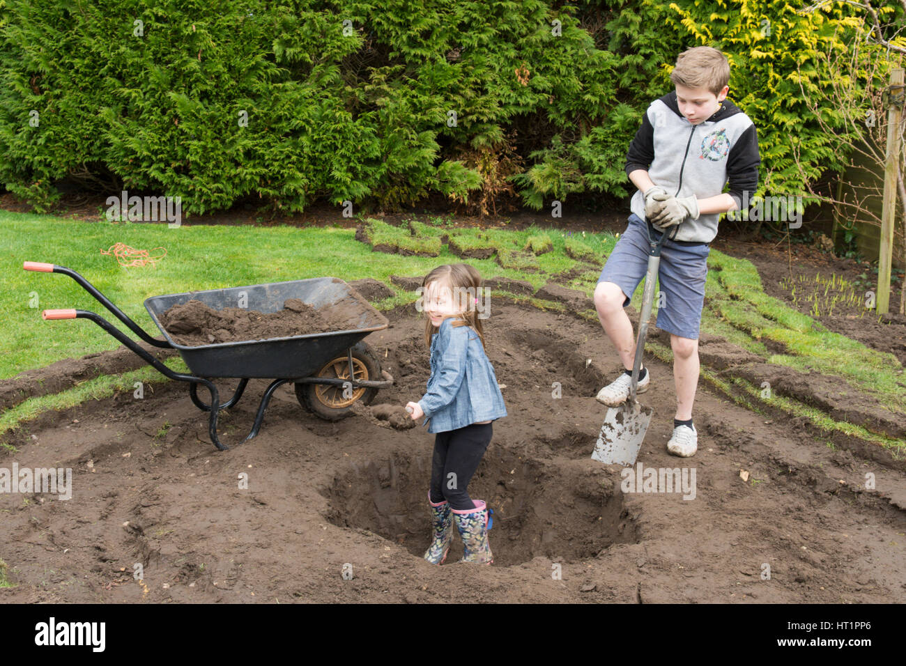 Jeune fille et garçon creuser l'étang de la faune dans le jardin Banque D'Images