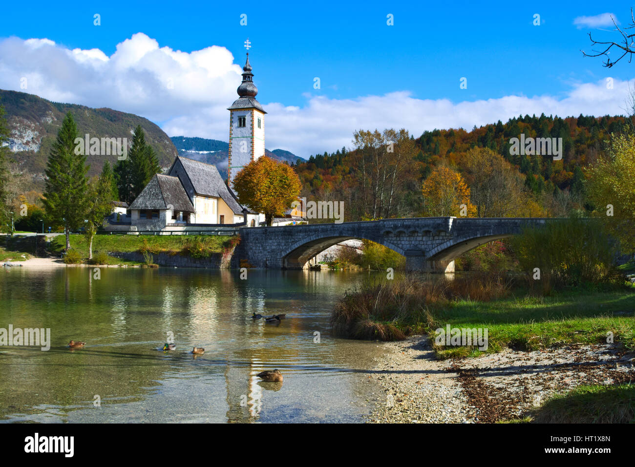 L'automne vue sur le pont de pierre et l'église de Saint-Jean le Baptiste au lac de Bohinj (bohinjsko jezero), Slovénie Banque D'Images