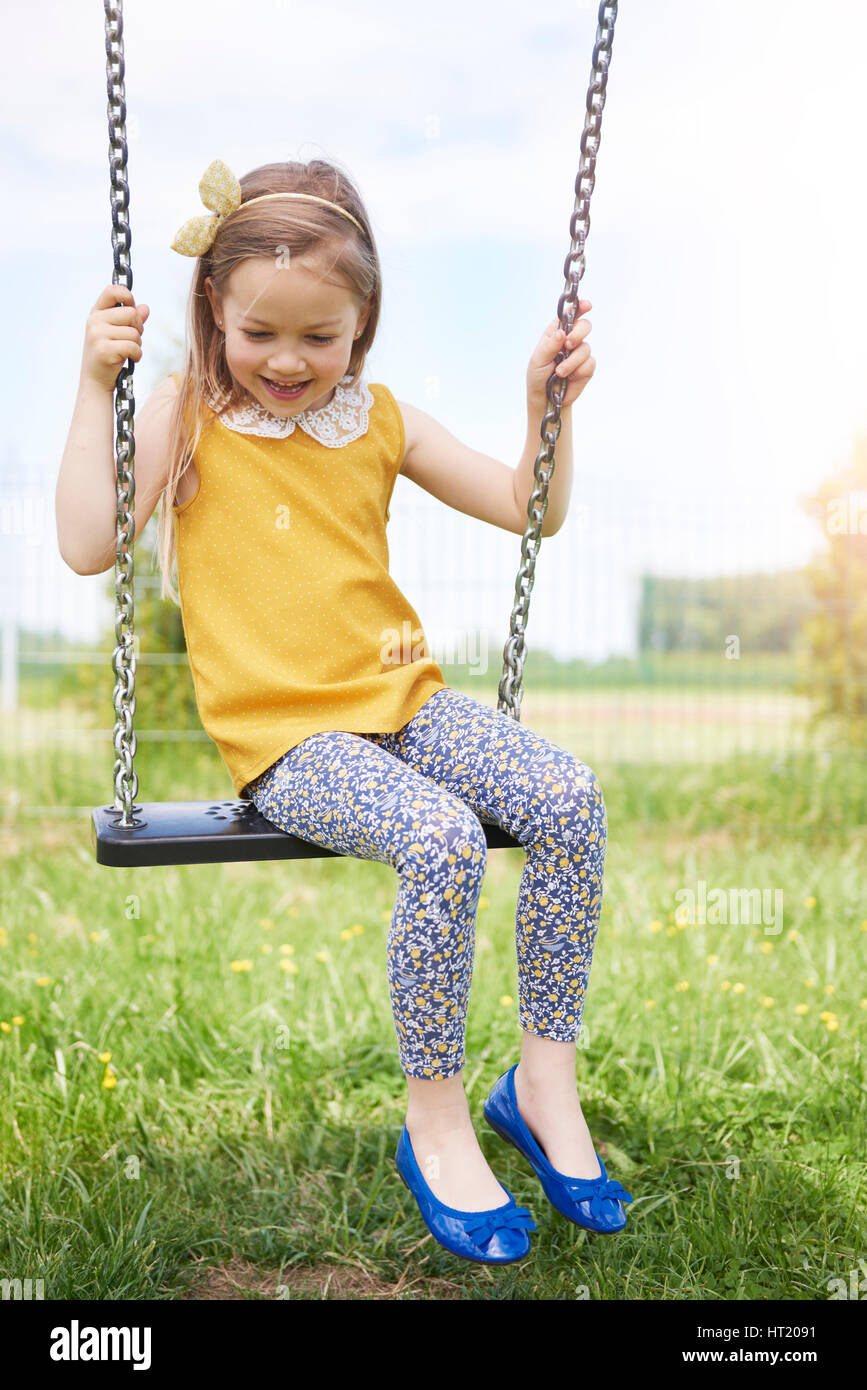 Swinging little girl in summer day Banque D'Images