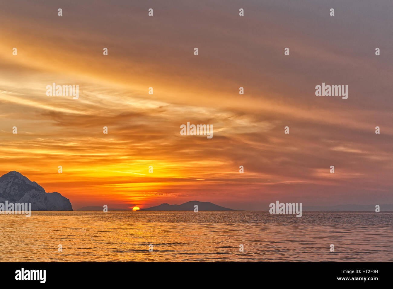 Coucher du soleil sur la plage avec de belles jaune et orange ciel dramatique. Silhouette d'une île très en avance en vue. Banque D'Images