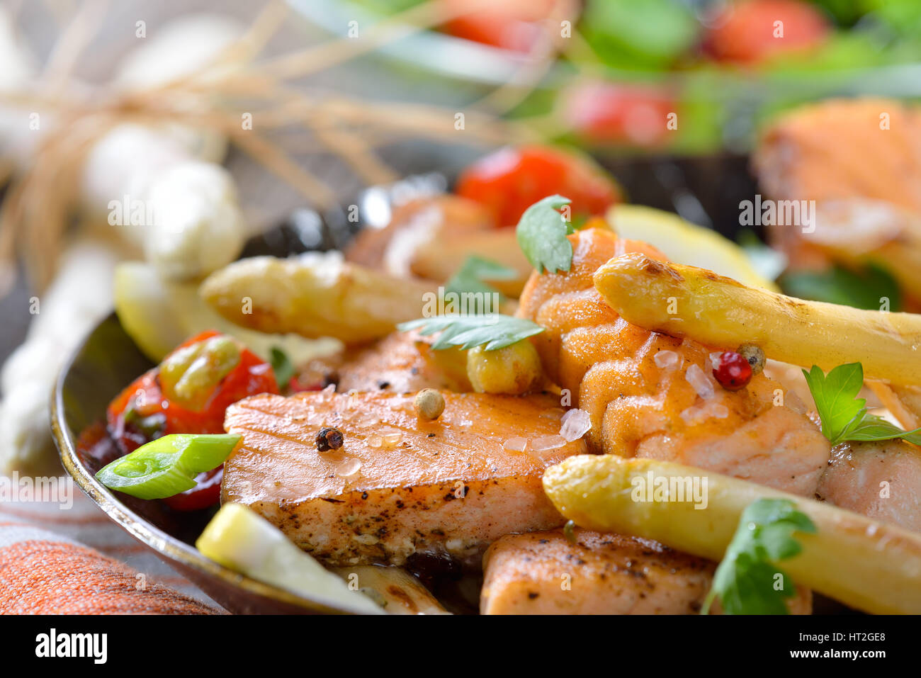 Asperges blanches rôties avec du saumon poêlé servi dans une poêle avec une petite salade roquette Banque D'Images