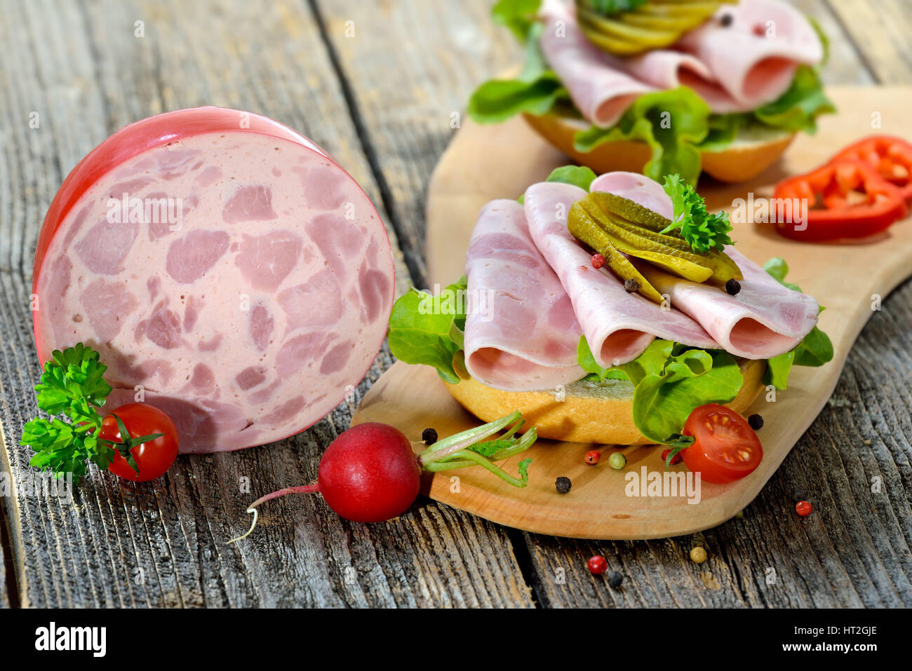 Rouleaux d'une tranche de jambon et des cornichons saucisse servie sur une planche en bois rustique Banque D'Images