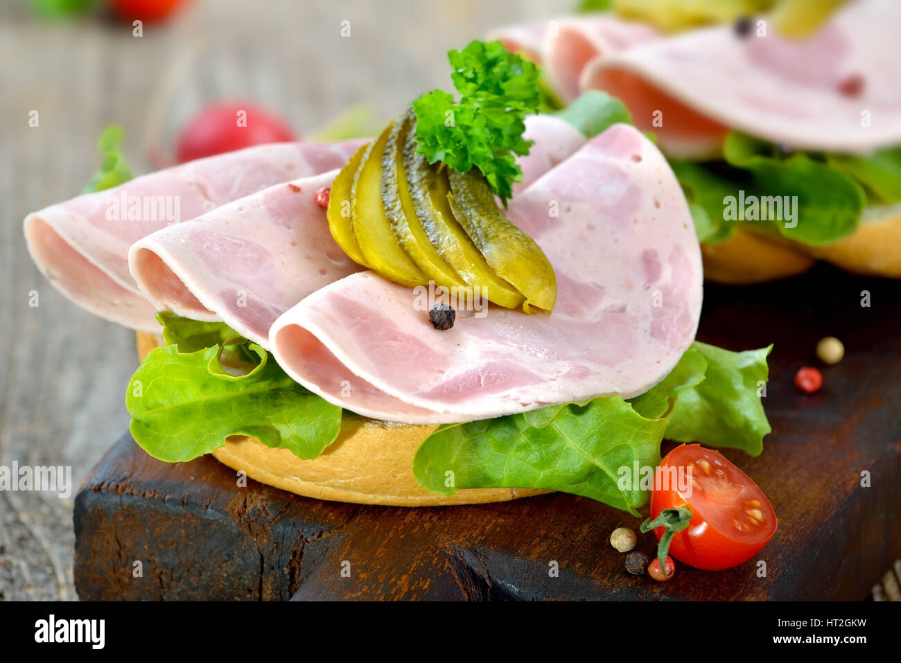 Rouleaux d'une tranche de jambon et des cornichons saucisse servie sur une planche en bois rustique Banque D'Images