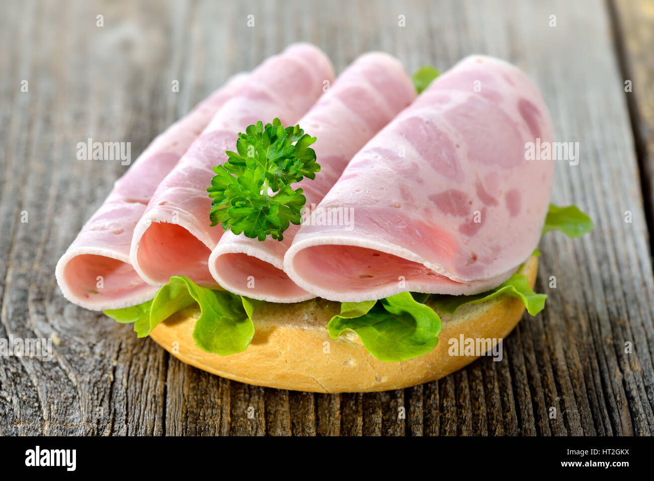 Rouleau avec saucisse jambon tranché et feuille de laitue servi sur une table en bois rustique Banque D'Images
