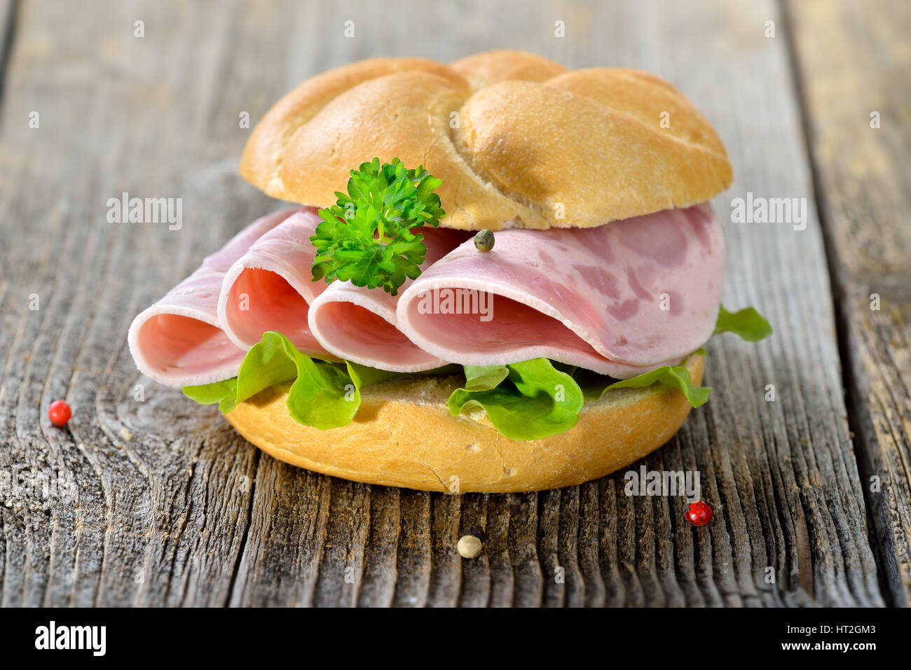 Rouleau avec saucisse jambon tranché et feuille de laitue servi sur une table en bois rustique Banque D'Images