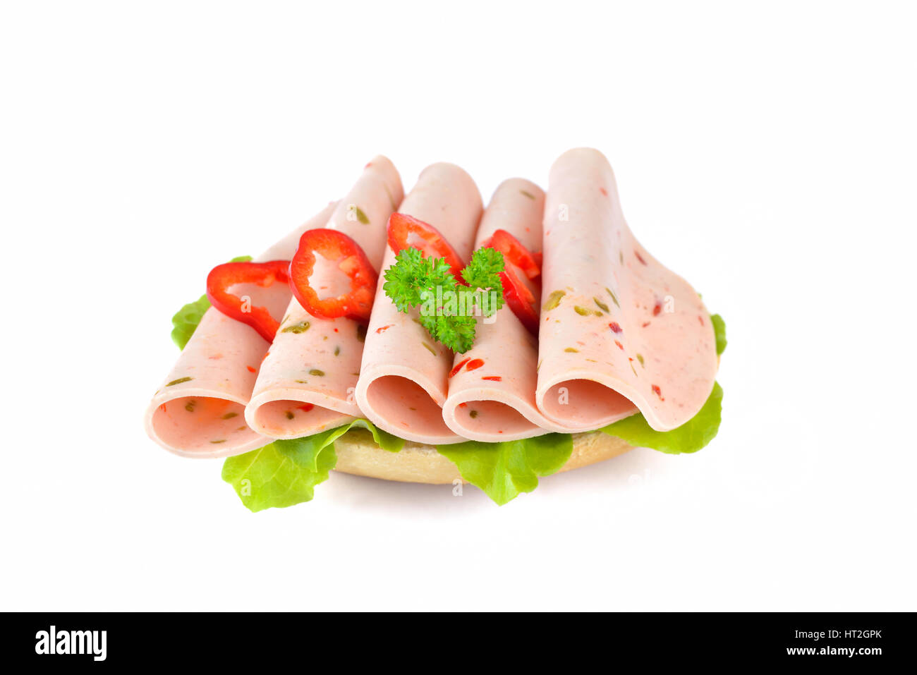 Petit pain frais avec des tranches de poivron saucisse et une feuille de laitue sur fond blanc Banque D'Images