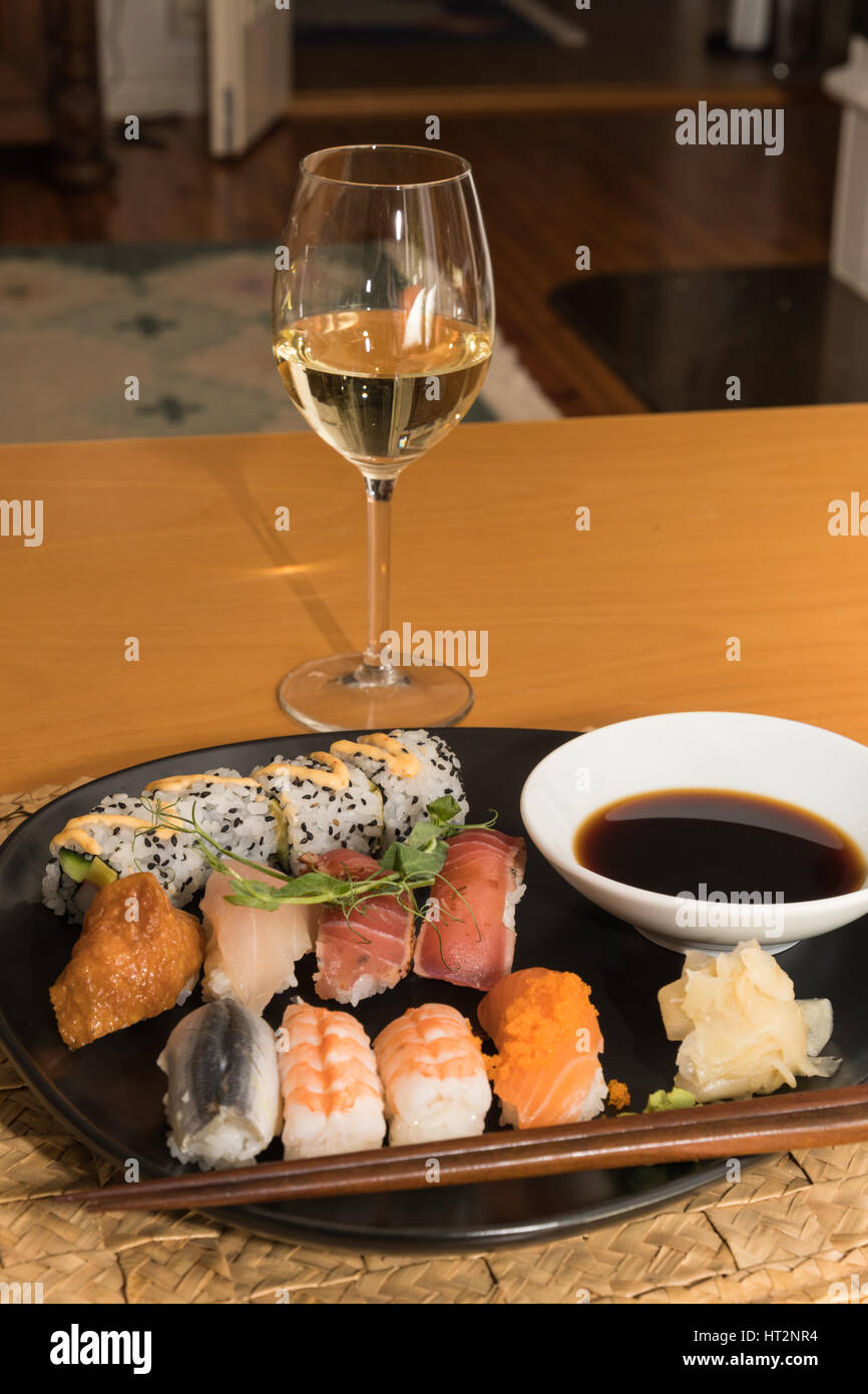 Verre de vin blanc et une plaque avec sushi sur une table Photo Stock -  Alamy