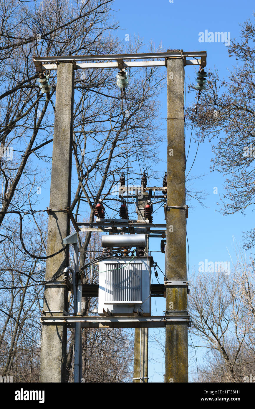 Transformateur haute tension monté sur deux poteaux en béton dans l'aménagement forestier - le printemps ! Banque D'Images