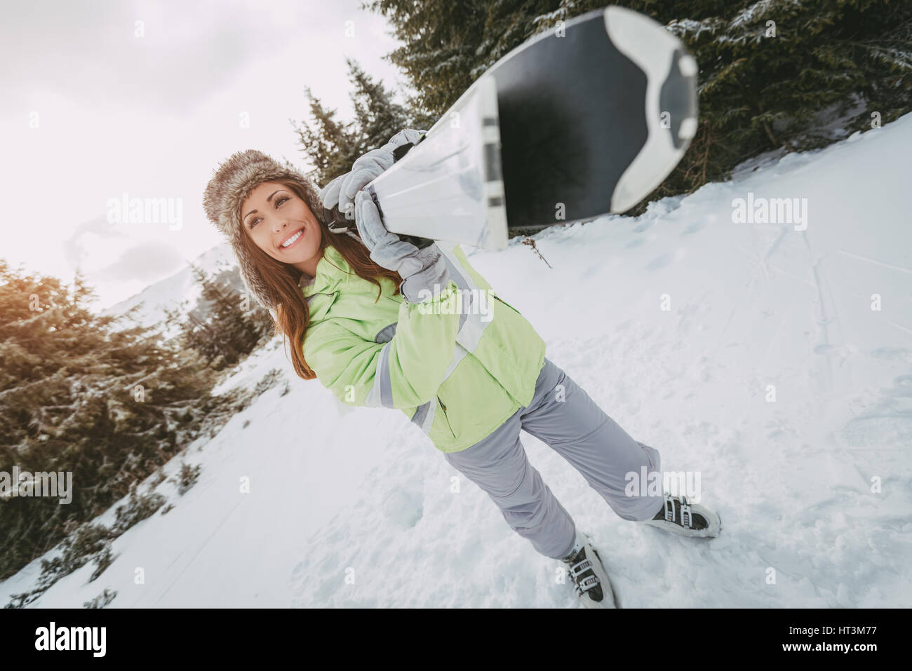 Belle jeune femme profitant de vacances de ski. Elle tenait avec des skis et à l'écart avec sourire. Banque D'Images