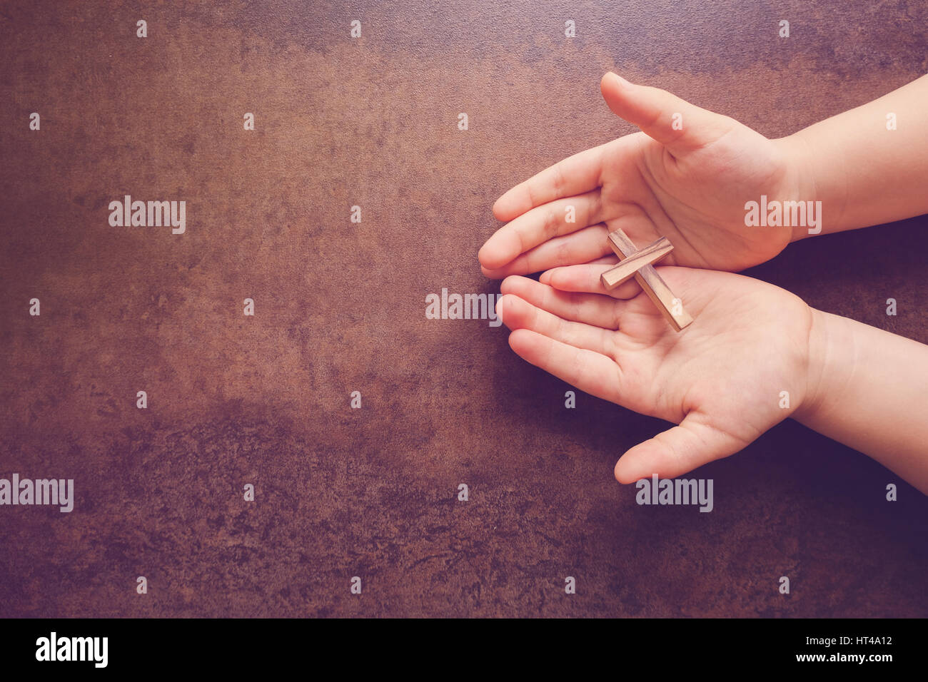 Croix de bois à prier les mains des enfants, copie espace tonification sombre contexte Banque D'Images