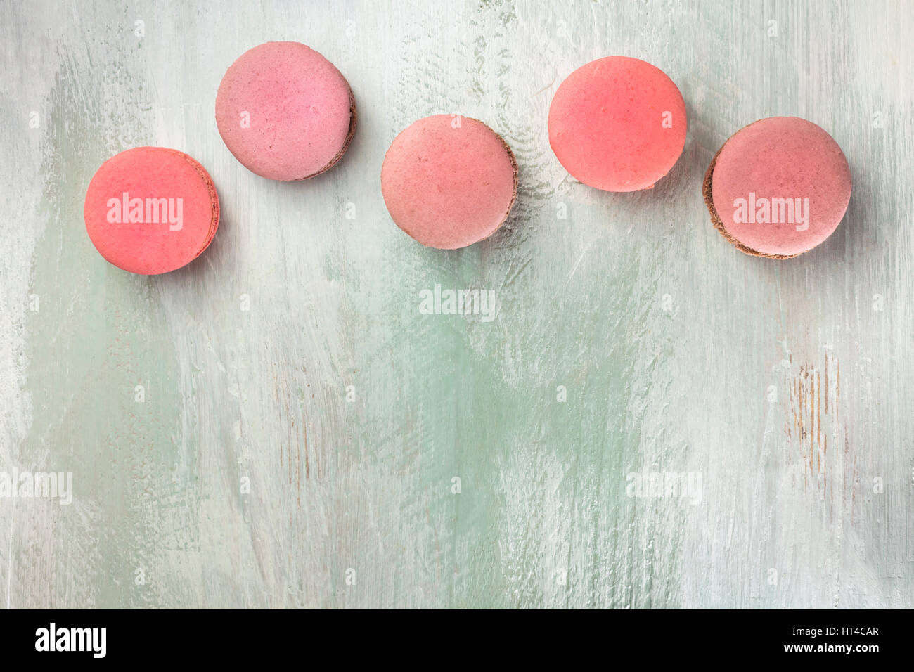 Une photo de macarons roses, tourné à partir de ci-dessus, sur un fond bleu sarcelle texture, avec une place pour le texte Banque D'Images