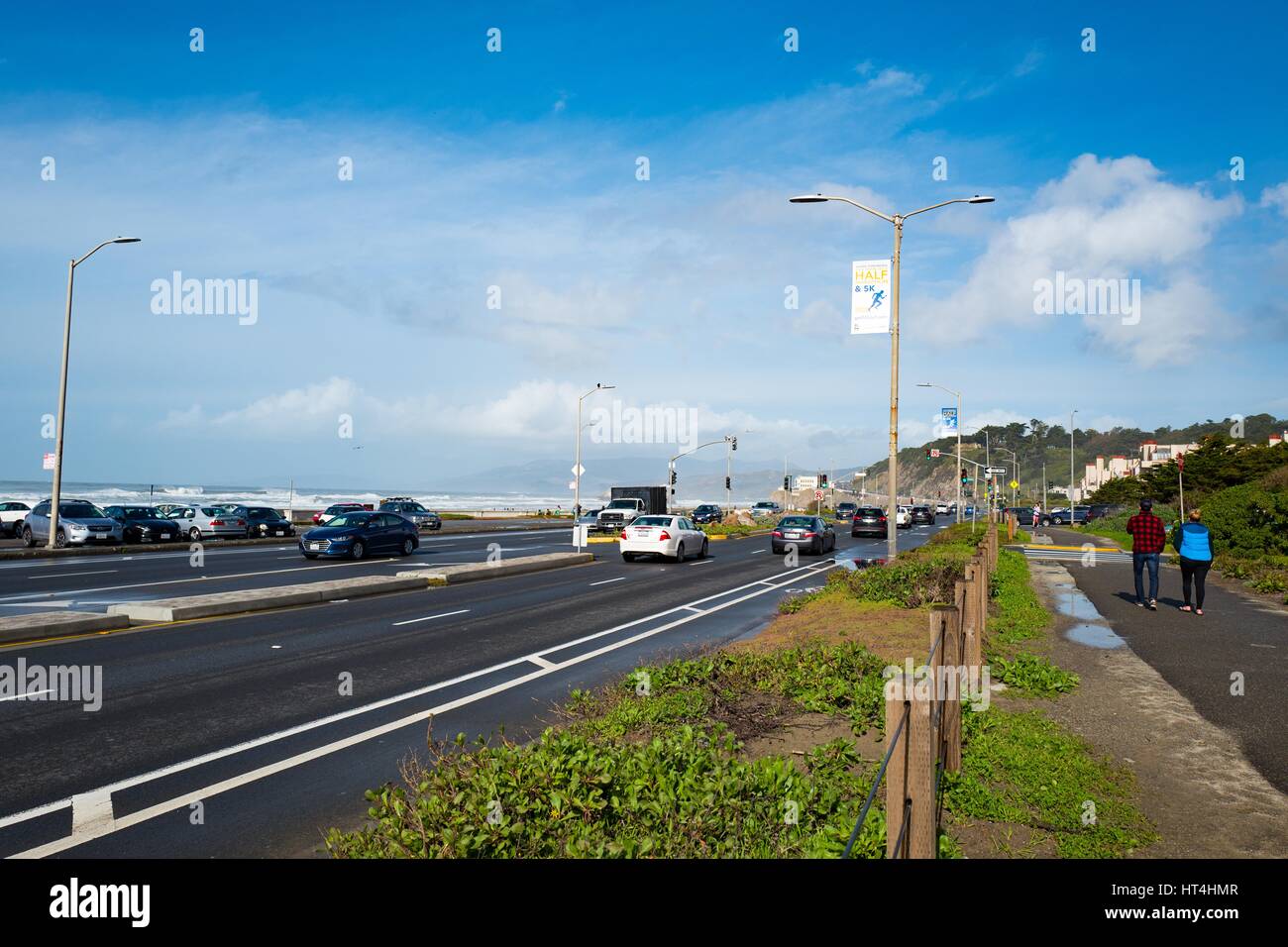 Deux personnes se promener près de la grande plage de l'océan à l'autoroute en direction de la falaise Chambre restaurant (visible dans la distance) dans le Land's End quartier de San Francisco, Californie, le 22 janvier 2017. Banque D'Images