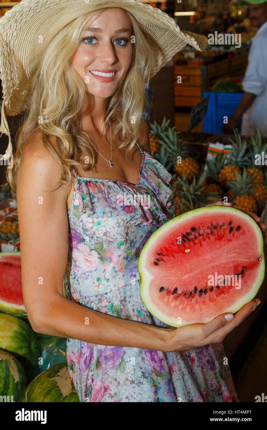 Une jeune blonde aux cheveux longs femme adultes dans une robe d'été et  portant un chapeau d'acheter des produits sains et nutritifs au farmers  market Photo Stock - Alamy