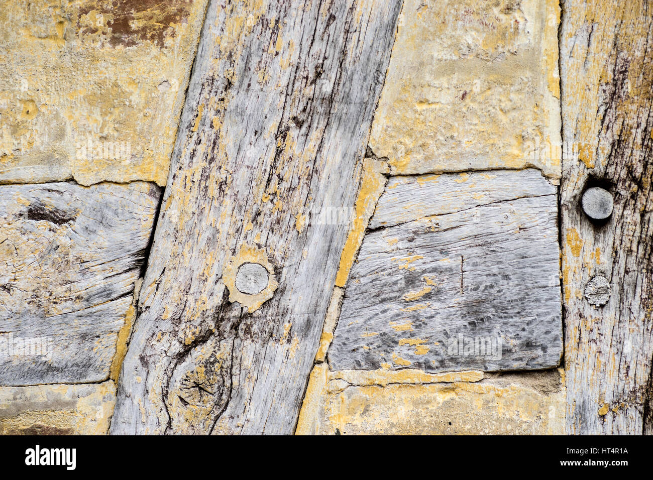 Détail de vieux bois de chêne fendu dans un bâtiment à colombages. Structure en bois de chêne avec remplissage de torchis. Peint avec badigeon jaune Banque D'Images