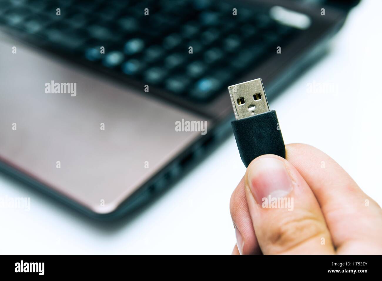 Man holding prise USB. Ordinateur portable en arrière-plan Banque D'Images