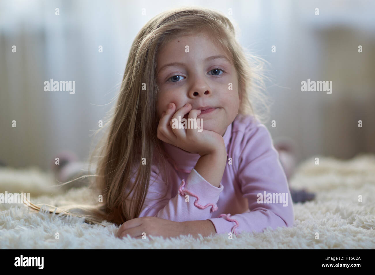 Petite fille aux cheveux longs sur le lit Banque D'Images