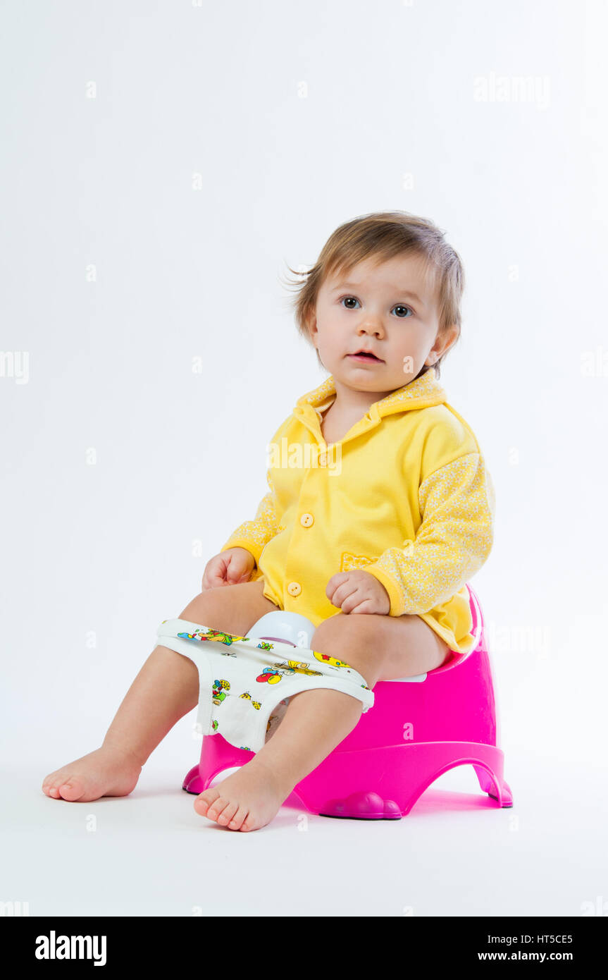 Little smiling girl sitting on un pot. Isolé sur fond blanc. Banque D'Images