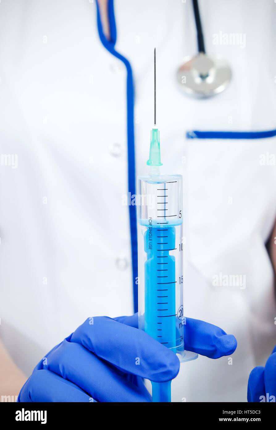 Femme médecin avec des gants médicaux et seringue injection holding stethoscope Banque D'Images