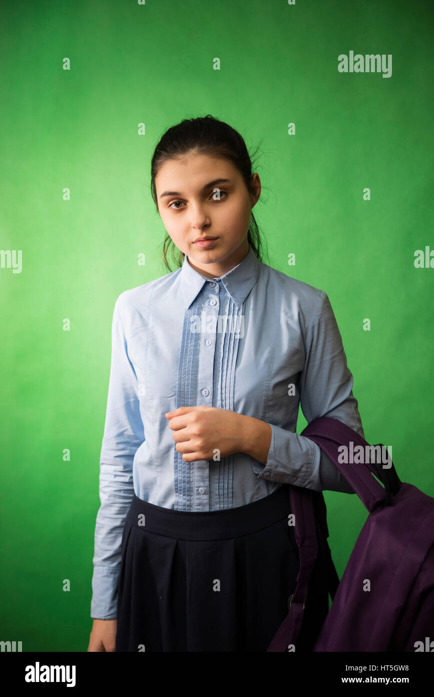 Une teen lycéenne en chemise bleue est debout avec un sac à dos violet sur ses épaules sur un arrière-plan chroma key vert Banque D'Images