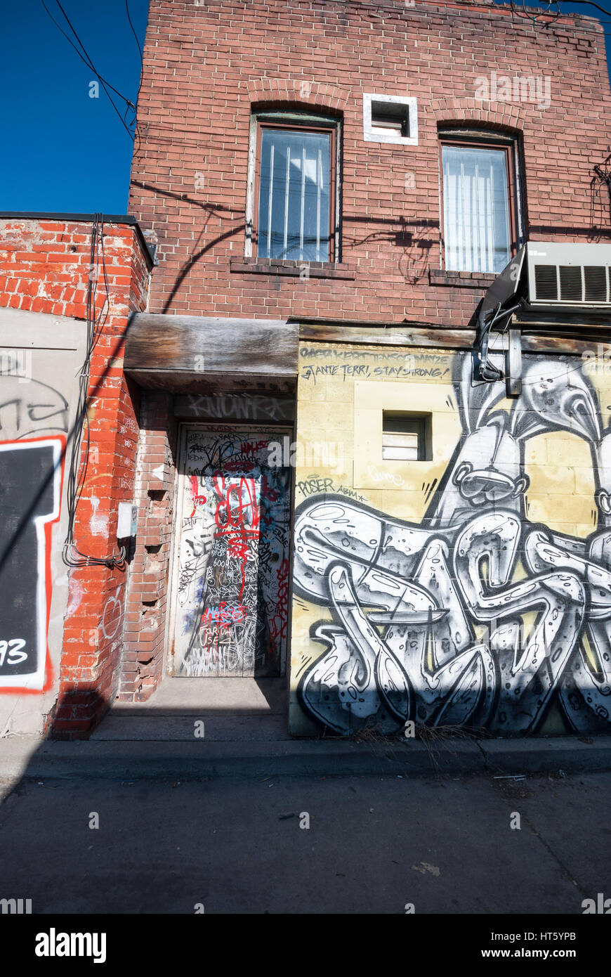 Un mur couvert de graffitis et porte sur un immeuble dans une ruelle de Kensington Market, à Toronto (Ontario) Canada. Banque D'Images