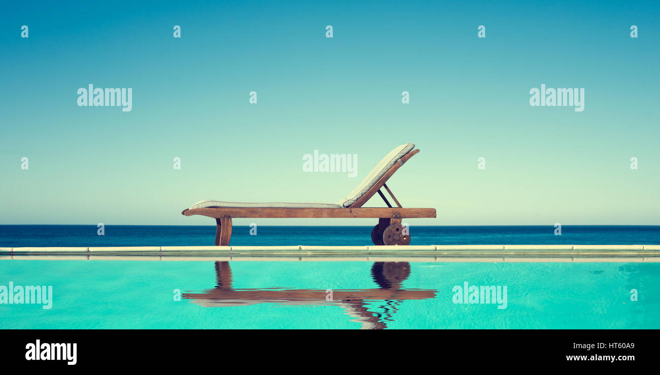 Chaise longue près d'une piscine, de la mer et fond de ciel bleu Banque D'Images