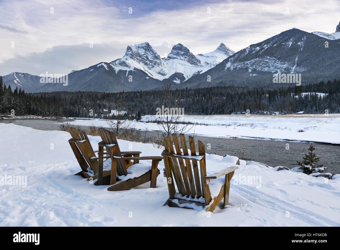 Chaises Adirondack sur rive nord de la rivière Bow, à Canmore (Alberta) à l'égard de 3 montagnes soeurs Banque D'Images