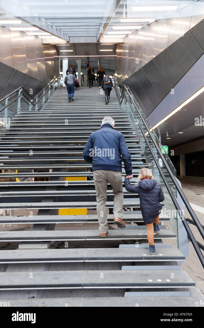 Homme plus âgé et petite fille monter les escaliers jusqu'à la borne de la gare centrale d'Utrecht en Hollande Banque D'Images