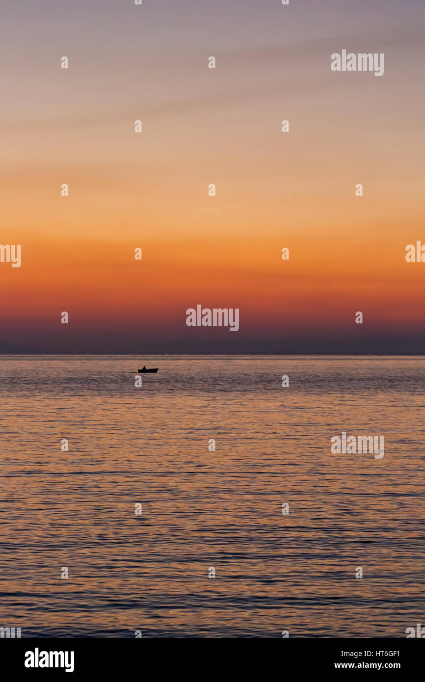 Petit bateau sunset silhouette est une pagaie bateau de pêcheur au bord de l'eau avec un violet et rose ciel nocturne dans l'arrière-plan Banque D'Images