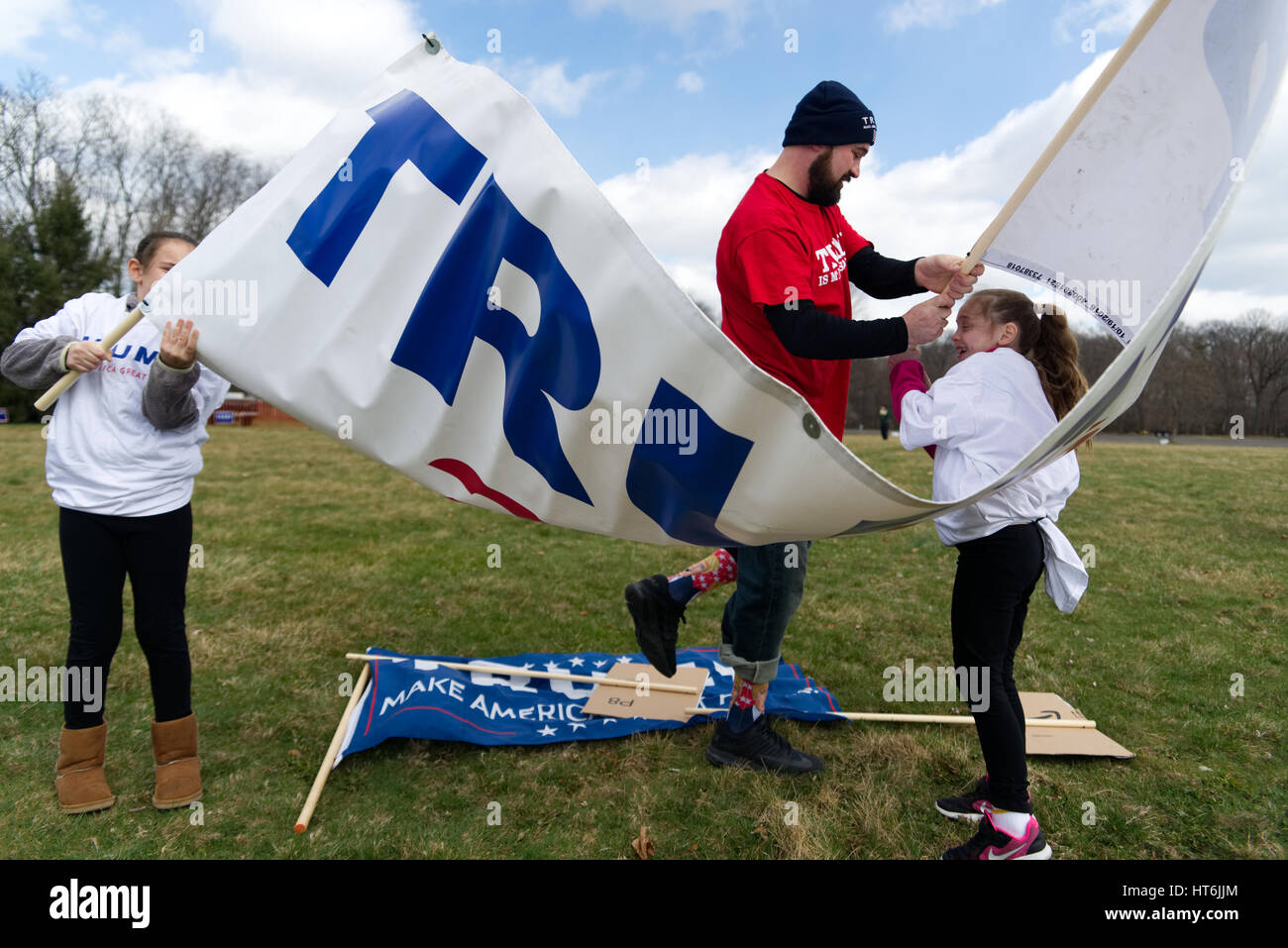 Kaylee et Eva comme Pigiannantonio aide Pete, au nord-est de Philadelphie, lutte avec le vent comme ils se déroulent un grand TRUMP 2016 banner, en prévision d'un pro Banque D'Images