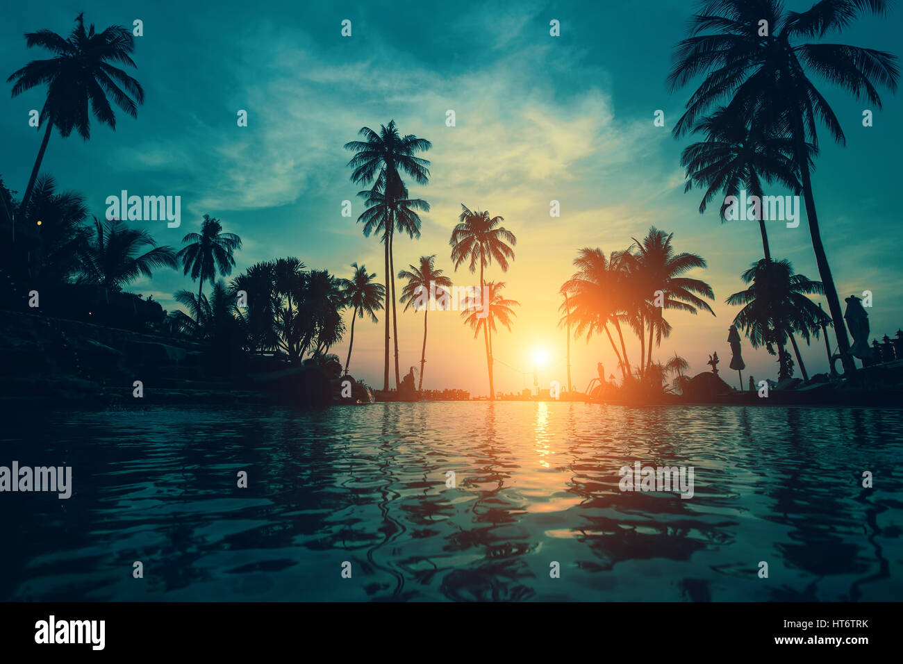 Crépuscule sur une plage tropicale avec des silhouettes de palmiers réflexions dans l'eau. Banque D'Images