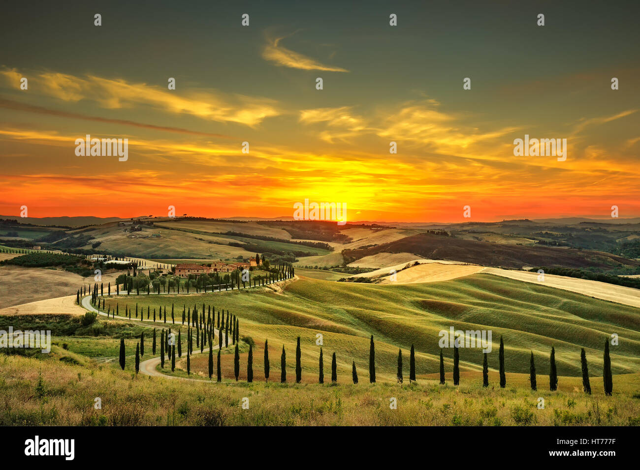 La toscane, paysage rural coucher du soleil. Campagne ferme, cyprès, arbres champ vert, la lumière du soleil et de nuages. L'Italie, l'Europe. Banque D'Images