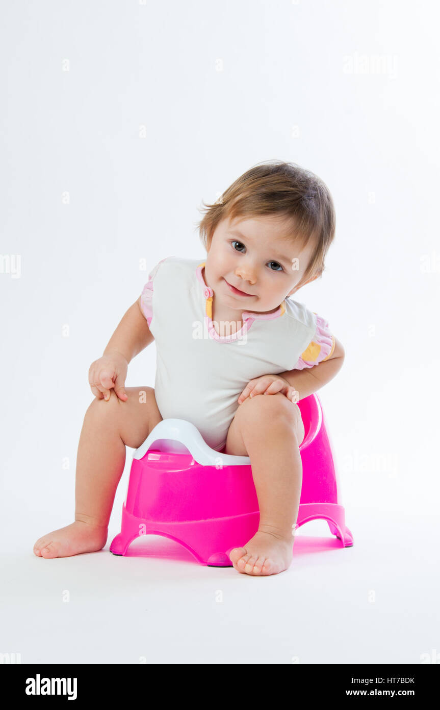 Little smiling girl sitting on un pot. Isolé sur fond blanc. Banque D'Images