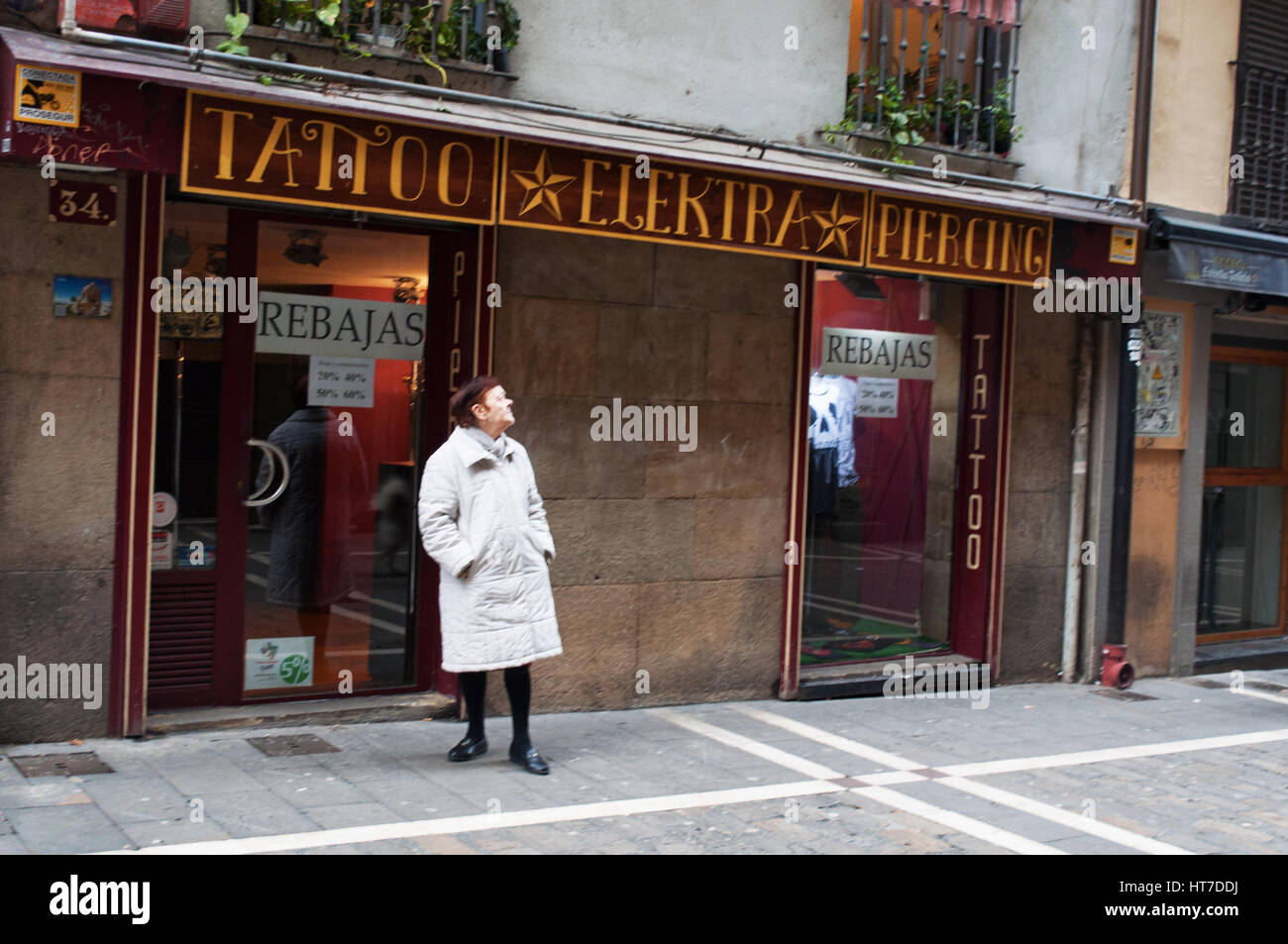 Espagne : une vieille femme devant un magasin de tatouage dans les ruelles de la vieille ville de Pampelune, ville célèbre pour la San Fermin fiesta avec ses taureaux courent Banque D'Images