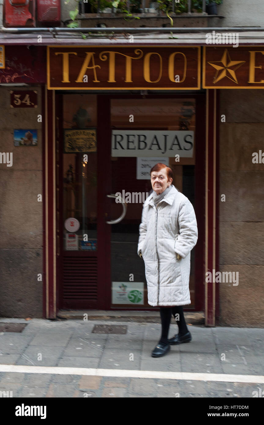 Espagne : une vieille femme devant un magasin de tatouage dans les ruelles de la vieille ville de Pampelune, ville célèbre pour la San Fermin fiesta avec ses taureaux courent Banque D'Images