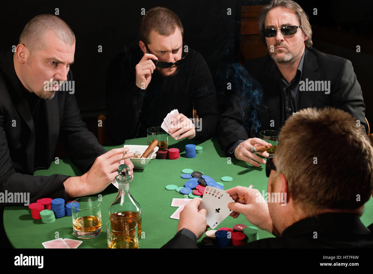 Photo de trois joueurs de poker homme regardant partout en colère à la quatrième joueur. Cartes ont été modifiées pour être générique. Banque D'Images